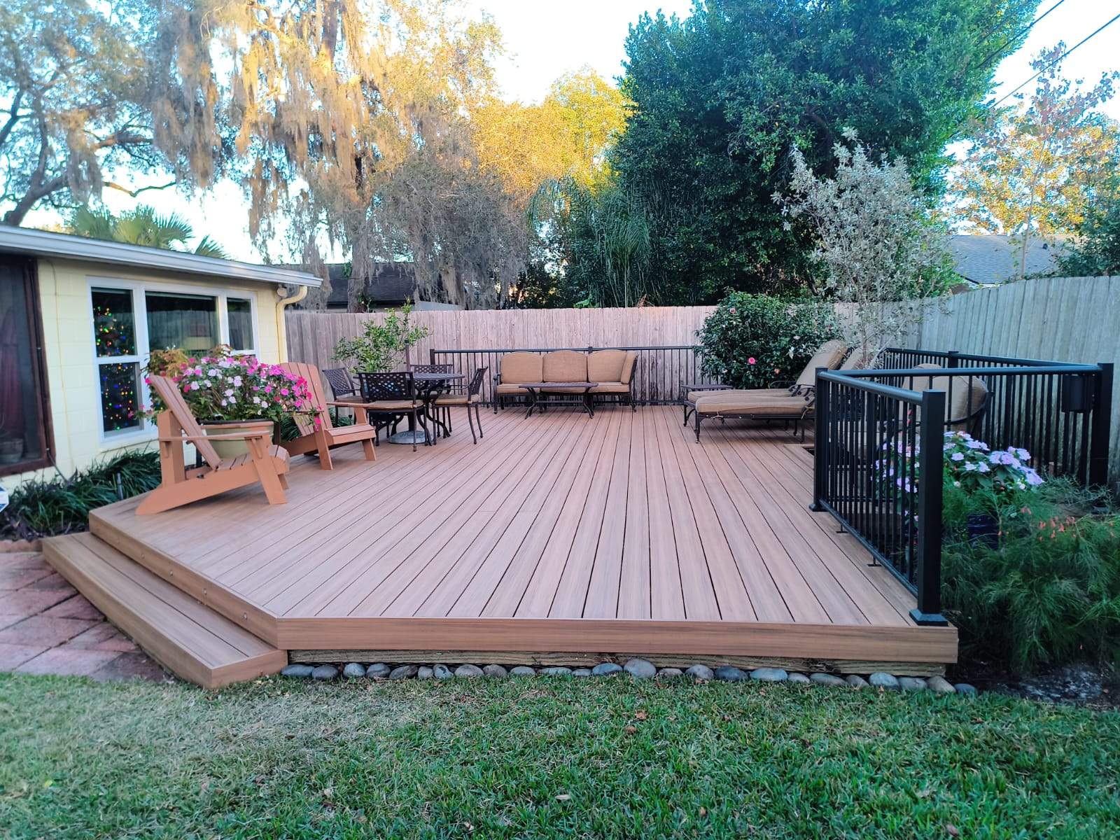 Composite backyard deck with Adirondack chairs and metal railing